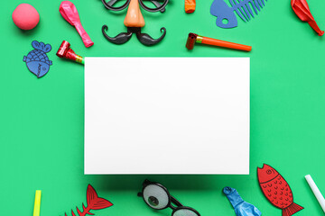 Blank card with paper fishes, funny glasses and party decor on green background. April Fools Day...