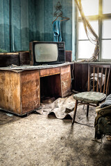 Old tv on broken table in abandoned room