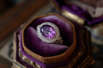 Elegant amethyst ring with diamond halo displayed on a rich purple satin pillow