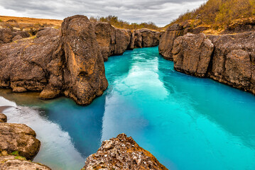 River with blue glacier water flows trough canyon in Iceland