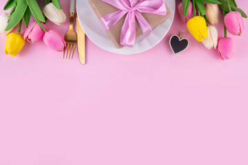 Mother day table setting background. Pink Mother's day border flat lay for brunch, lunch, dinner menu, invitation mockup. Beautiful table setting with golden cutlery, plate, tulip flowers and gift box