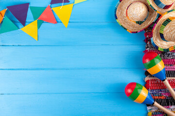 Mexican holiday background with serape striped blanket or poncho, sombrero hat, maracas on old blue wood backdrop. Mexico Cinco de Mayo festival, Mexican Independence day background