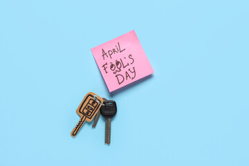 Sticky note and carton key on blue background. April Fools Day prank