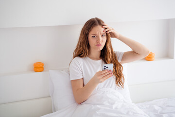 Naklejka premium Photo of dissatisfied girl sit bed under blanket hold smart phone receive bad news text morning bedroom house inside