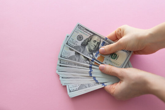 Hand holding money on pink background with space for text
