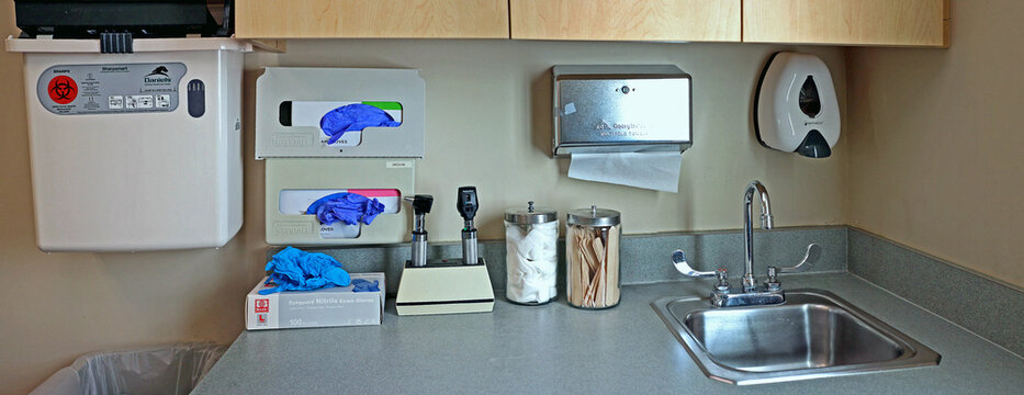 Medical exam room, counter with sink and various examination devices and instruments.