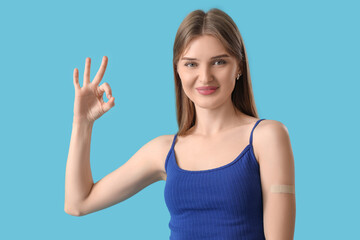 Fototapeta premium Pretty young woman with applied medical patch showing OK gesture on color background