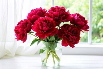Bouquet of red peonies in vase on windowsill