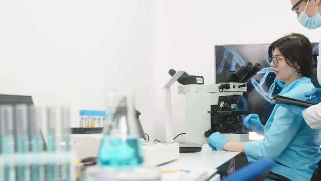 Medical science laboratory with diverse team of professional biotechnology scientists developing drugs, female biochemist working on computer demonstrating gene therapy interface.