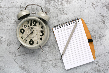 Notebook with text IF NOT NOW, WHEN? and alarm clock on grey background. Time management concept....