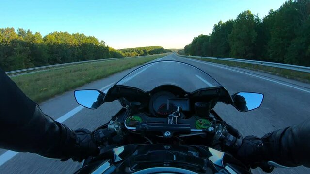 The viewpoint of motorcyclist driving motorbike at speed highway. Point of view of motorcycle rider rides fast in country road. Guy racing his motor bike during summer journey. Road trip concept. POV
