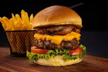 Hamburger accompanied by fries and soda in a studio photo with brown and black wood
