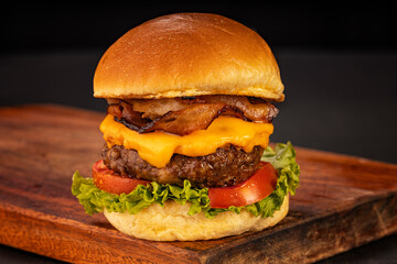 Hamburger accompanied by fries and soda in a studio photo with brown and black wood