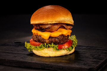 Hamburger accompanied by fries and soda in a studio photo with brown and black wood
