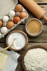 Ingredients for making dough and rolling pin on wooden table, flat lay