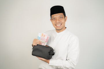 happy asian muslim man holding money, wearing arabic costume on isolated background