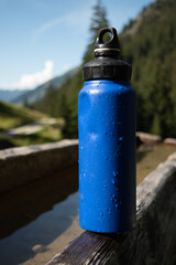 : Blue Water Bottle on Wooden Bench in Mountainous Landscape - 763332100