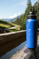 : Blue Water Bottle on Wooden Bench in Mountainous Landscape - 763332112