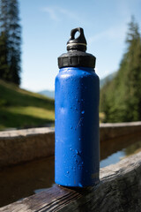 : Blue Water Bottle on Wooden Bench in Mountainous Landscape - 763332122
