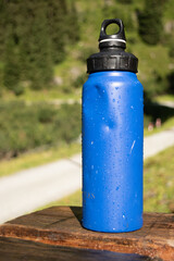  Reusable Blue Water Bottle on Rustic Wooden Surface with Alpine Background - 763332161