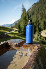 : Blue Water Bottle on Wooden Bench in Mountainous Landscape - 763332173