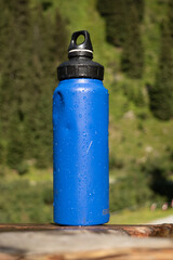  Reusable Blue Water Bottle on Rustic Wooden Surface with Alpine Background - 763332176