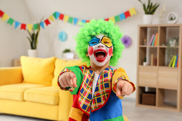 Funny little boy in clown costume pointing at viewer, closeup. April Fools' Day celebration