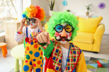 Funny little boy in clown costumes pointing at viewer, closeup. April Fools' Day celebration