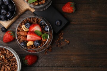 Tasty granola, berries and nuts on wooden table, flat lay. Space for text