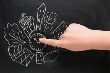 Female hand pointing at drawing on blackboard. Time management. Top view