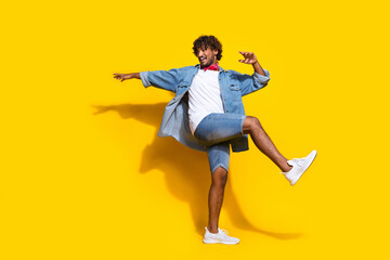 Fototapeta na wymiar Full size photo of nice young male dance good mood look empty space wear trendy denim outfit red scarf isolated on yellow color background