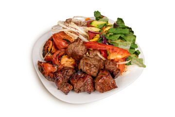 A plate of spicy beef tikka or beek skewer chunks with grilled vegetables and green salad isolated on white