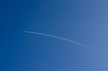 the white trail of the plane in the blue sky