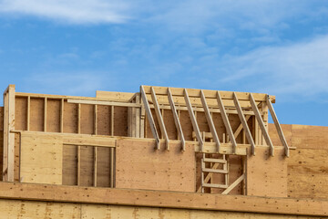 Fototapeta premium Rafters and plywood sheathing on the walls of a multi unit wood residential construction project with a lot of interesting detail 