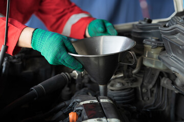 Hands of male mechanic working at garage. Male mechanics checks, repair and maintenance engine oil...