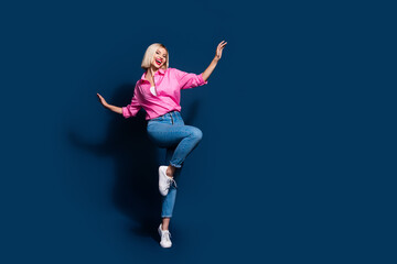 Full size photo of satisfied pretty girl dressed pink shirt jeans dancing at party on tiptoe isolated on dark blue color background