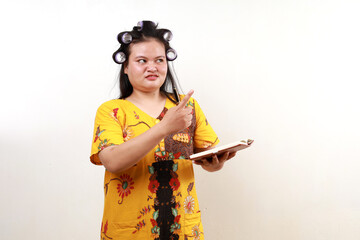 Angry asian housewife standing holding a book while pointing sideways