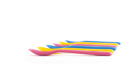 Set of colourful children plastic spoons laid down graphic side view isolated on white background. Concept of reusable plastic utensils, kids parties lunch dinner, sustainable living, child friendly