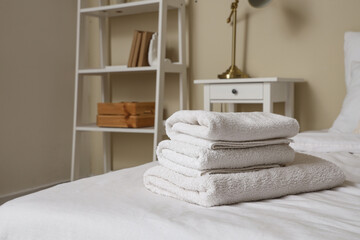 Stack of clean towels on bed in room, closeup