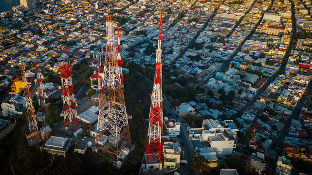 5g telecom tower above the crowded cityscape  - Powered by Adobe