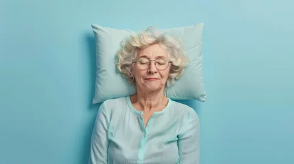 Poster Elderly woman sleeping on pillow isolated on pastel blue colored background Sleep deeply peacefully rest. Top above high angle view photo portrait of satisfied .senior wear blue shirt © Sittipol 