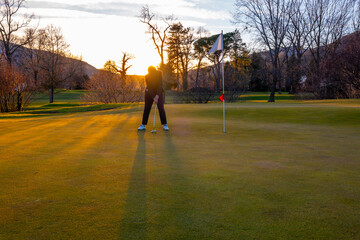 Female Golfer Concentration on the Putting Green on Golf Course in Sunset in Switzerland.