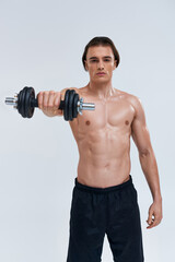 Fototapeta na wymiar attractive athletic man posing topless exercising actively with dumbbell and looking at camera