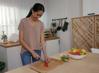 Young woman is cooking vegetable salad in the kitchen, holiday activity