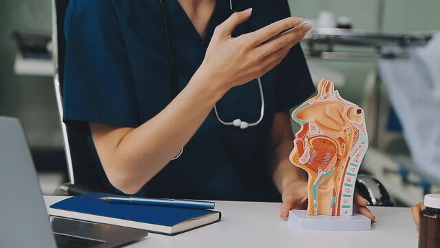 asian female doctor wearing face mask is showing a rectal model and explaining to elder senior man patient in hospital.