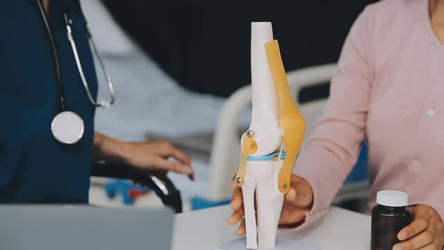 Human cruciate ligament injury treatment concept. Orthopedist showing to cruciate ligament in a knee-joint medical teaching model, close-up