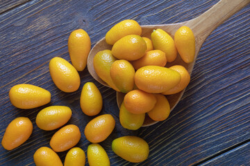 Fresh ripe kumquats in big heart shaped spoon on dark rustic table. Copy space