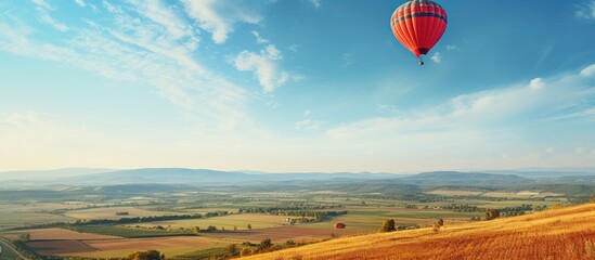 Hot air balloon soaring above a rural farmland - obrazy, fototapety, plakaty