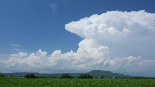 Video of cumulus cloud billowing across a vast rural landscape