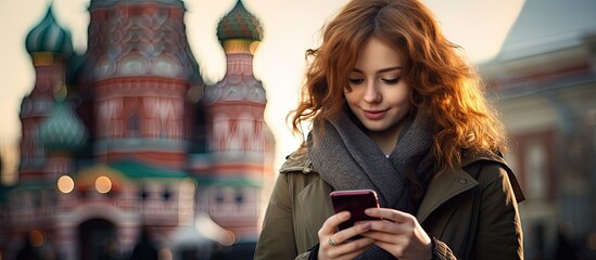 Woman checking phone outside a building, tourist capturing Moscow on smartphone - obrazy, fototapety, plakaty